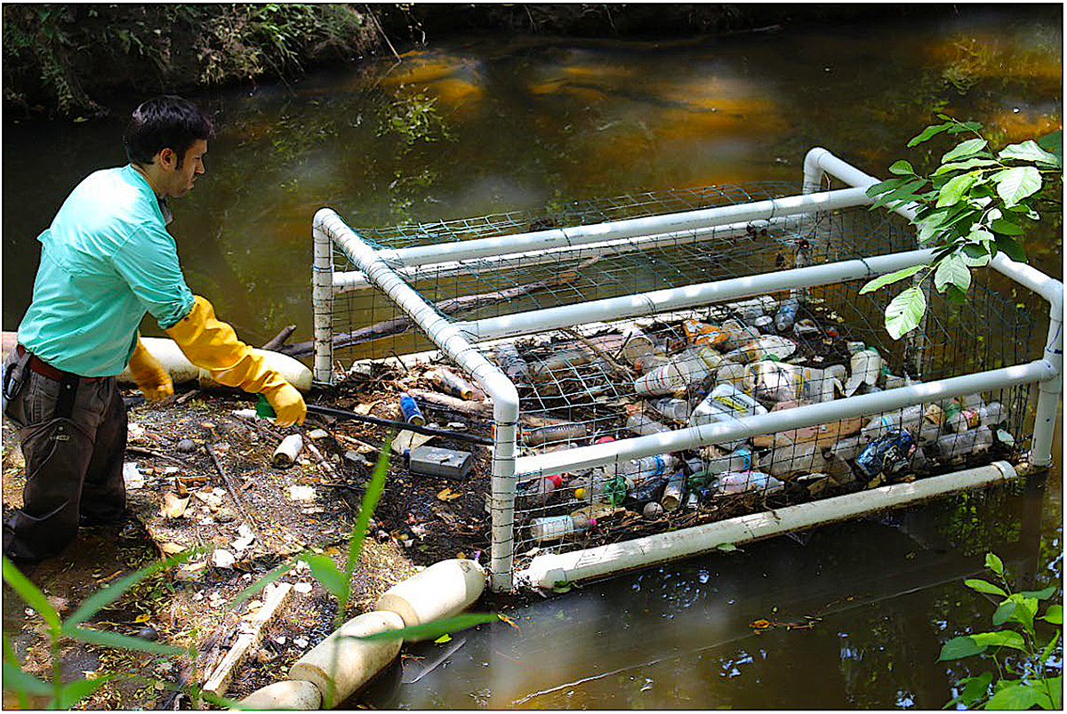 An unidentified man uses a Litter Gitter prototype to remove litter from Marsh Creek after a storm. Photo: North Carolina Sea Grant